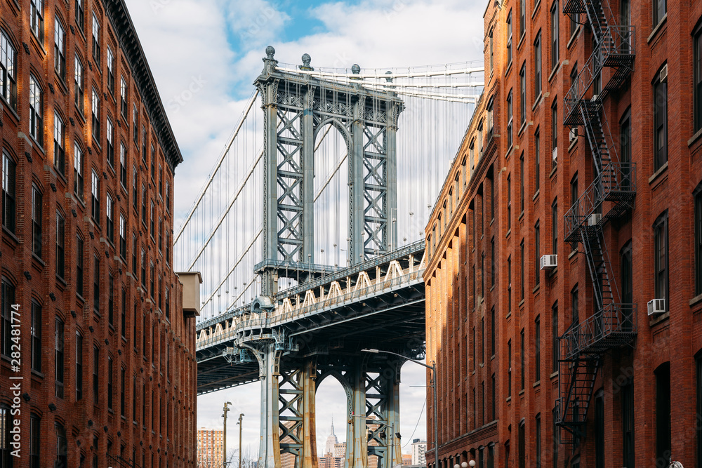 Brooklyn Bridge seen between two beautiful brown buildings at sunset